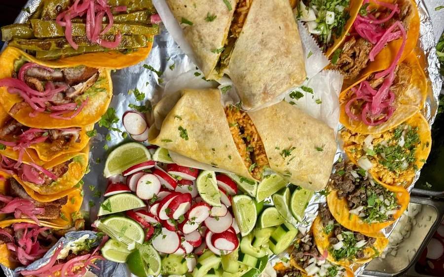 A full taco platter with burritos, limes, radish and pickled onion