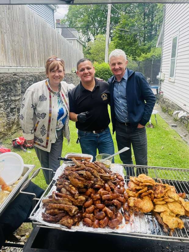 Ronaldo with two guests beside a grill full of ribs and chicken
