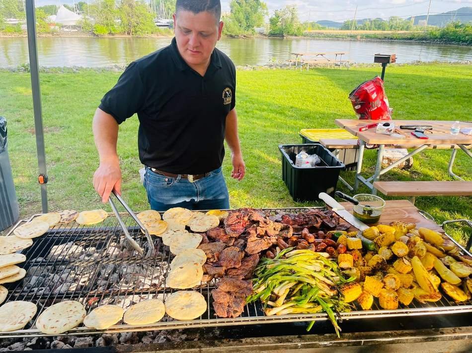 The grill loaded with meat, tortillas and vegetables by the river