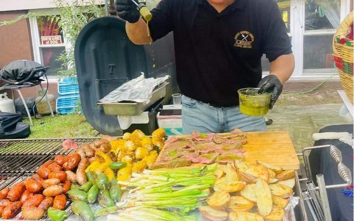 Ronaldo working the grill under the tent at a party